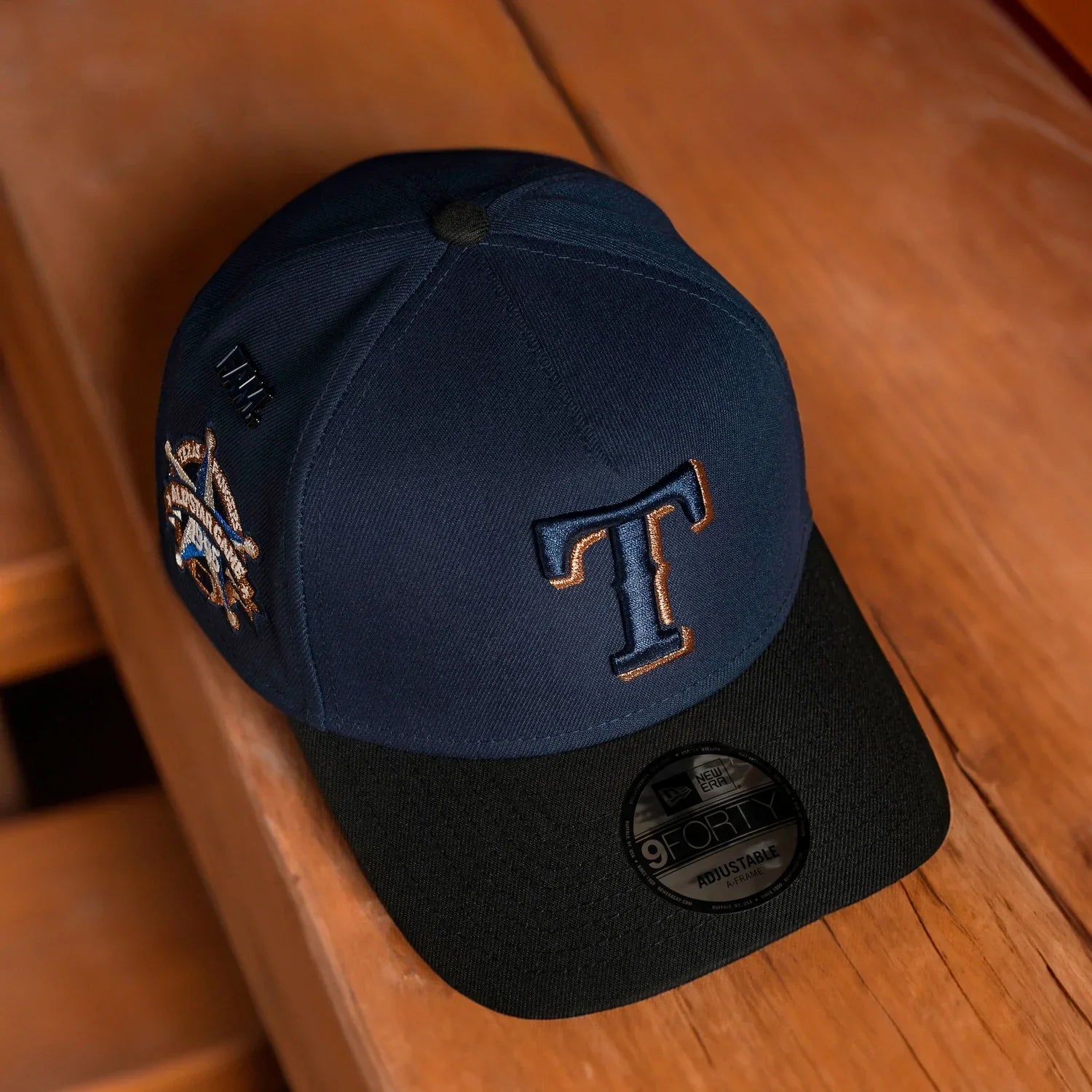 Navy and black baseball cap with embroidered logo on a wooden surface