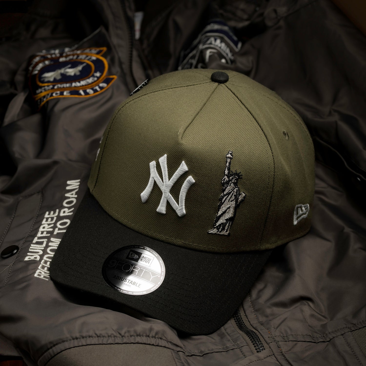 Green cap with New York Yankees logo and Statue of Liberty on a dark jacket