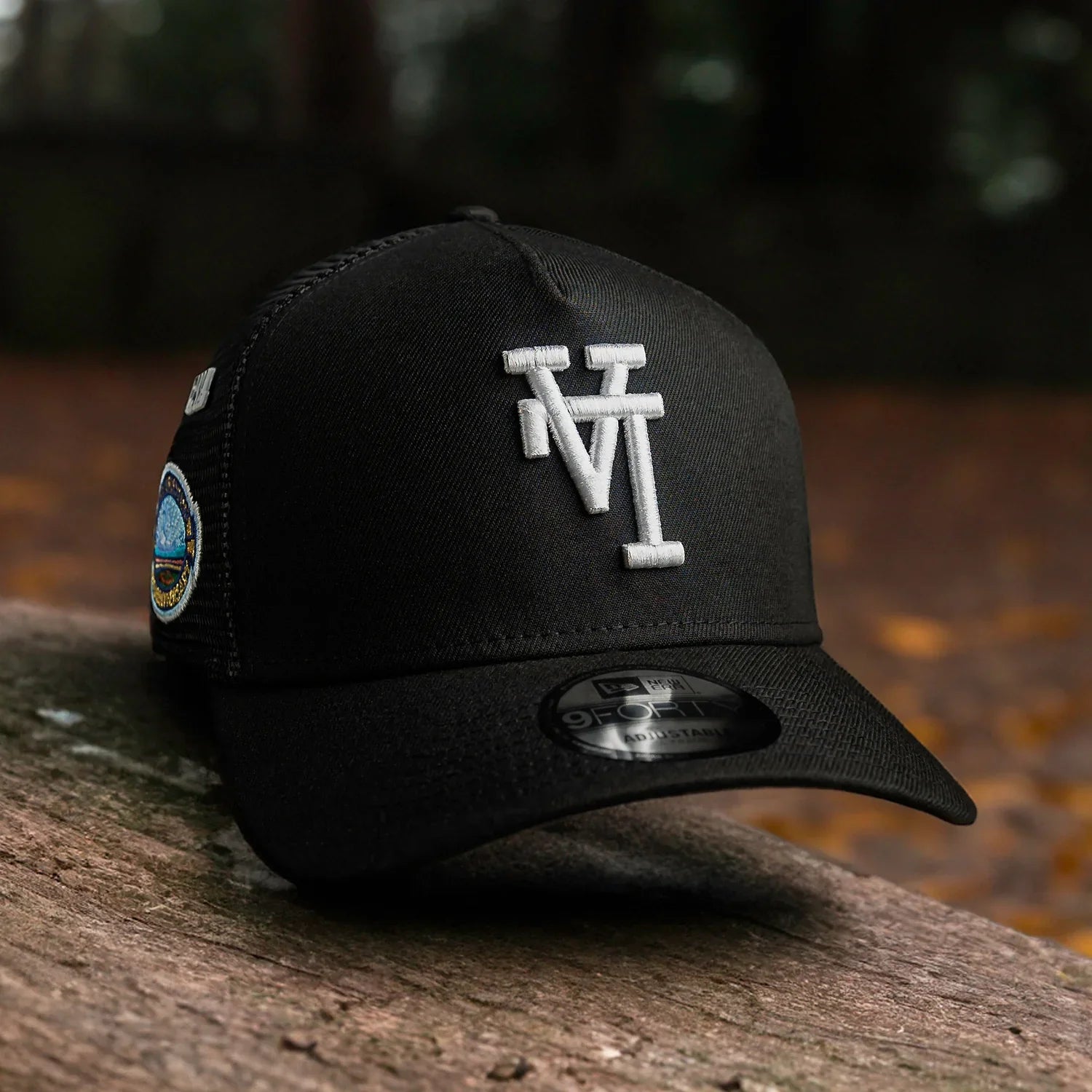 Black cap with white logo on a wooden surface