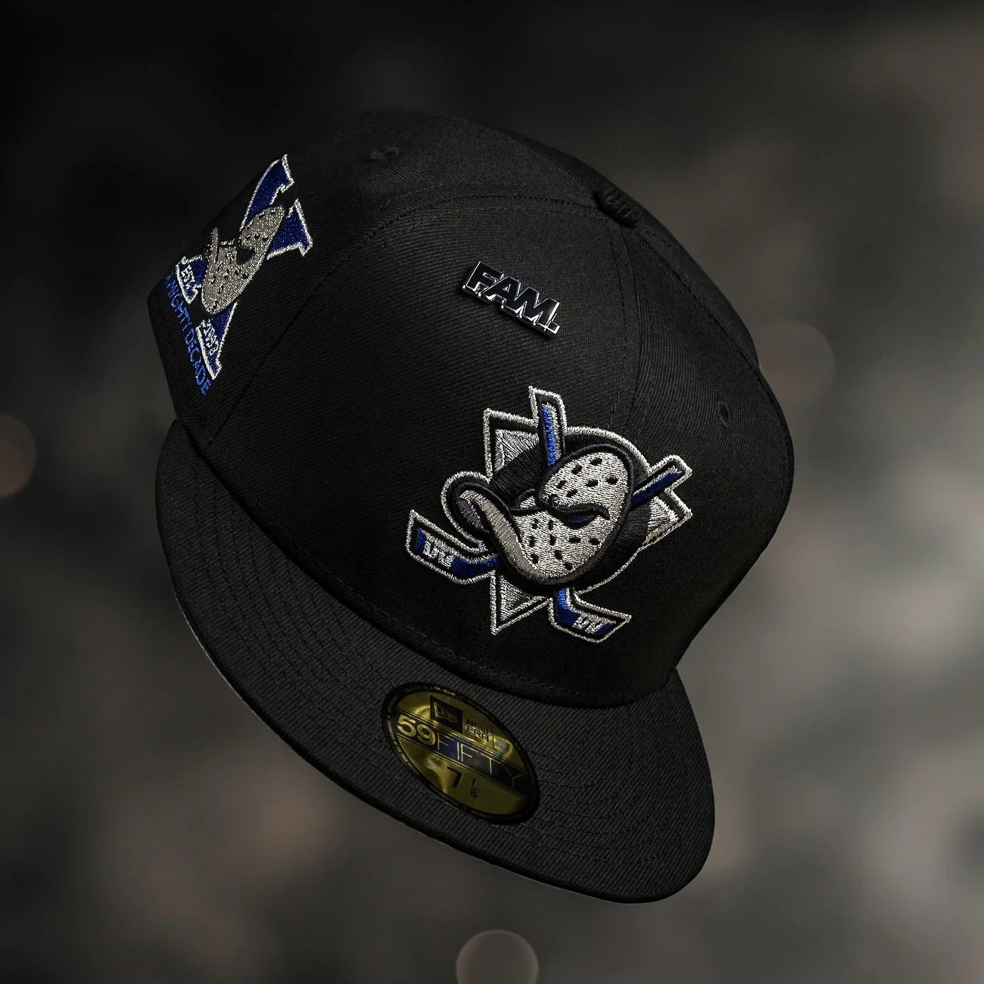 Black cap with embroidered logos on a dark background