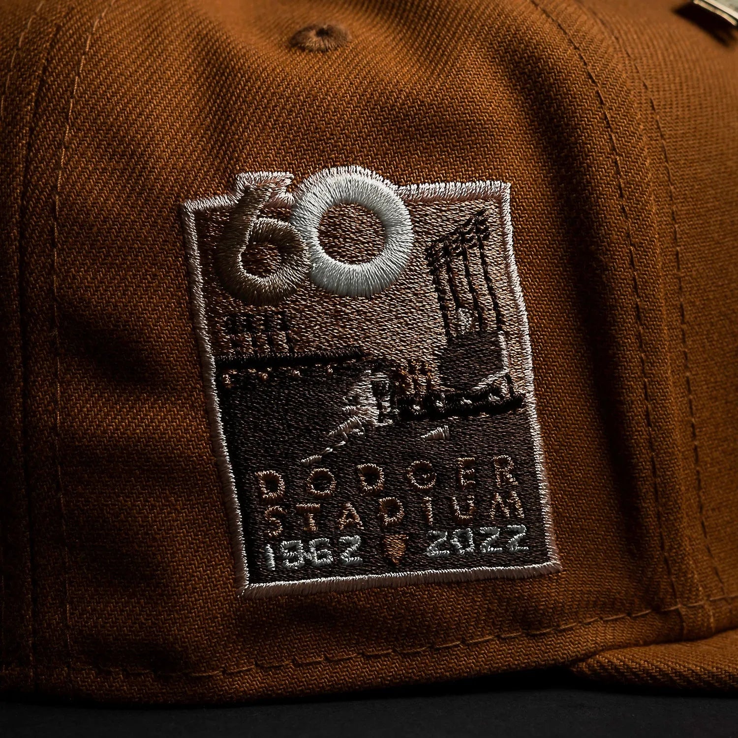 Brown cap with an embroidered patch featuring 'Dodger Stadium' and years on a dark background
