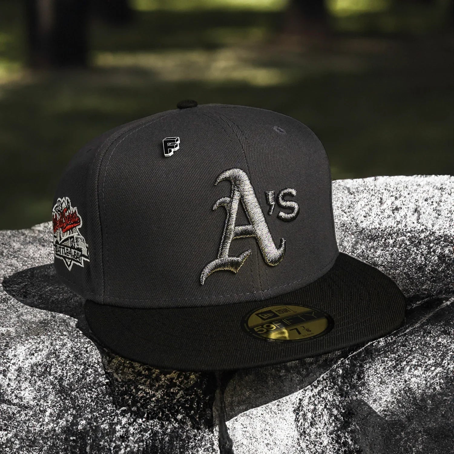 Gray baseball cap with 'A's' logo on a stone surface