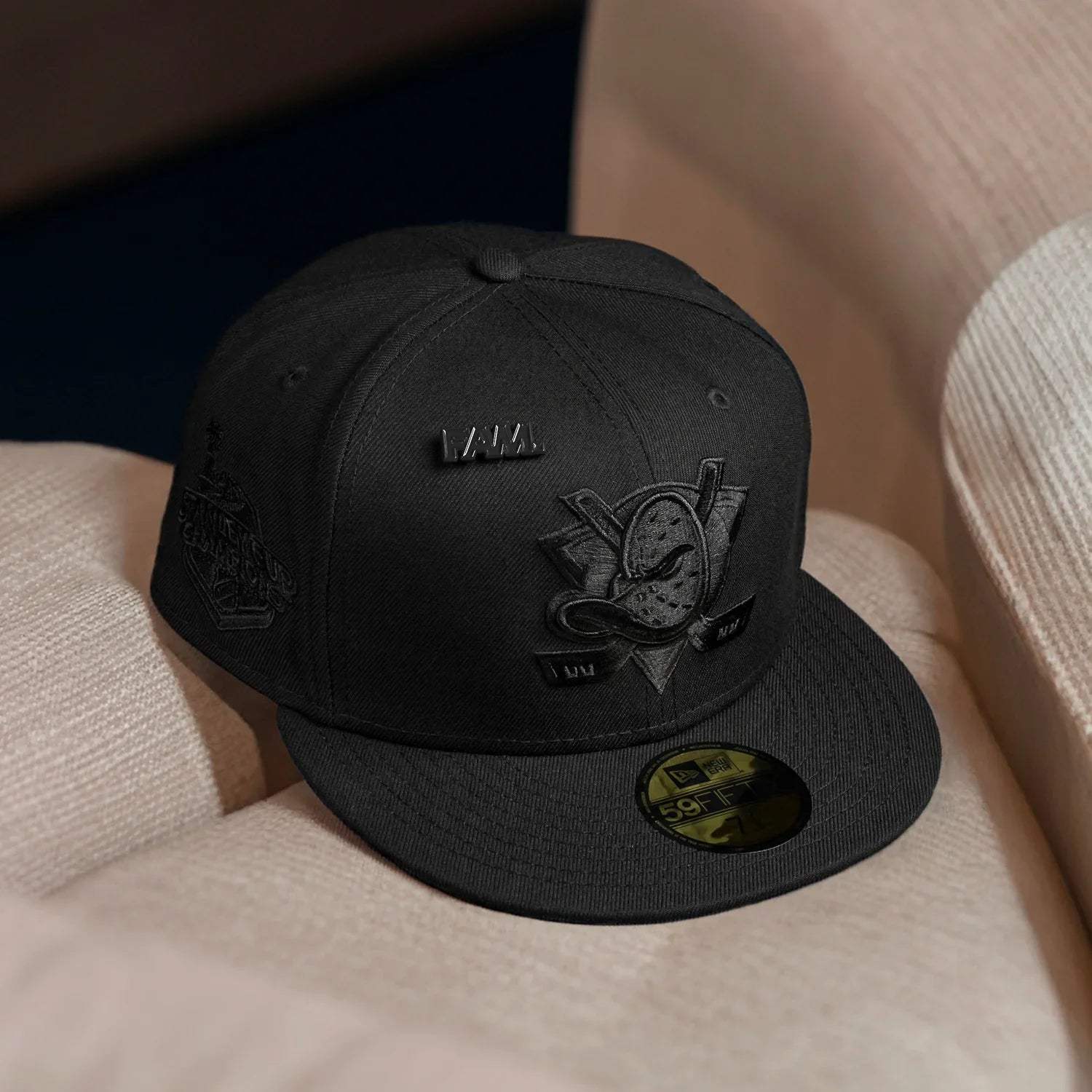 Black cap with a logo on a beige surface