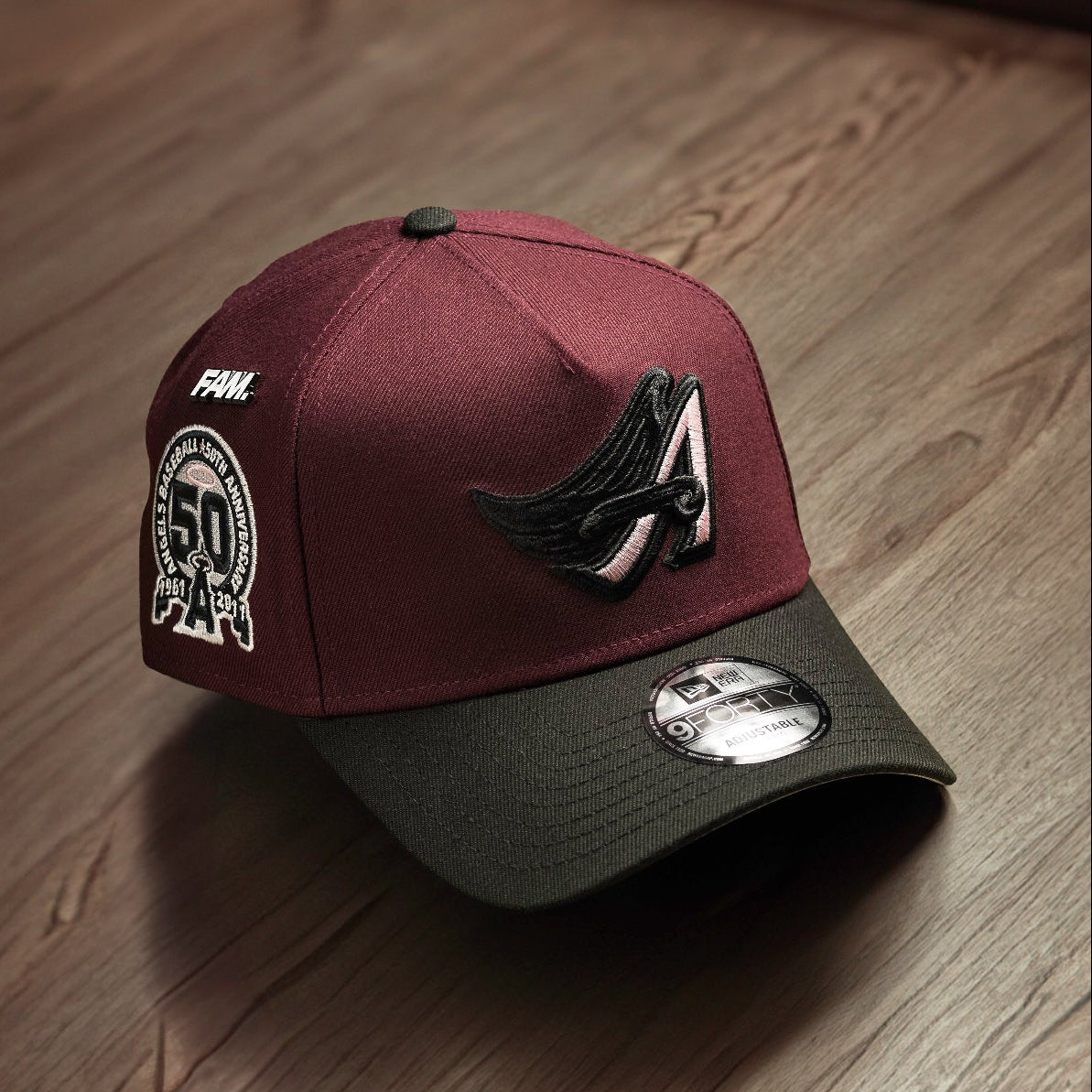 Maroon and black cap with logo on a wooden surface