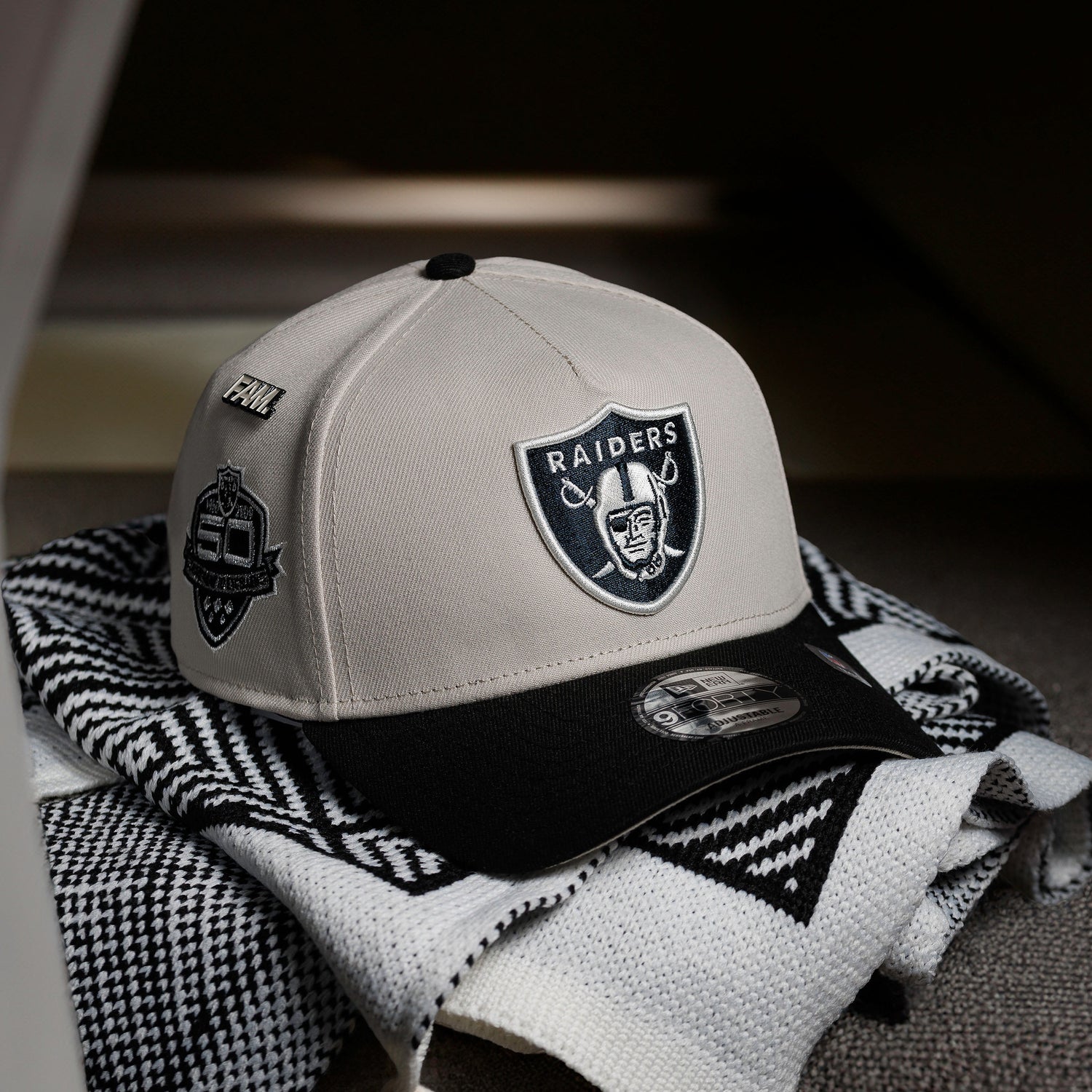 Beige and black cap with 'RAIDERS' logo on a patterned fabric background