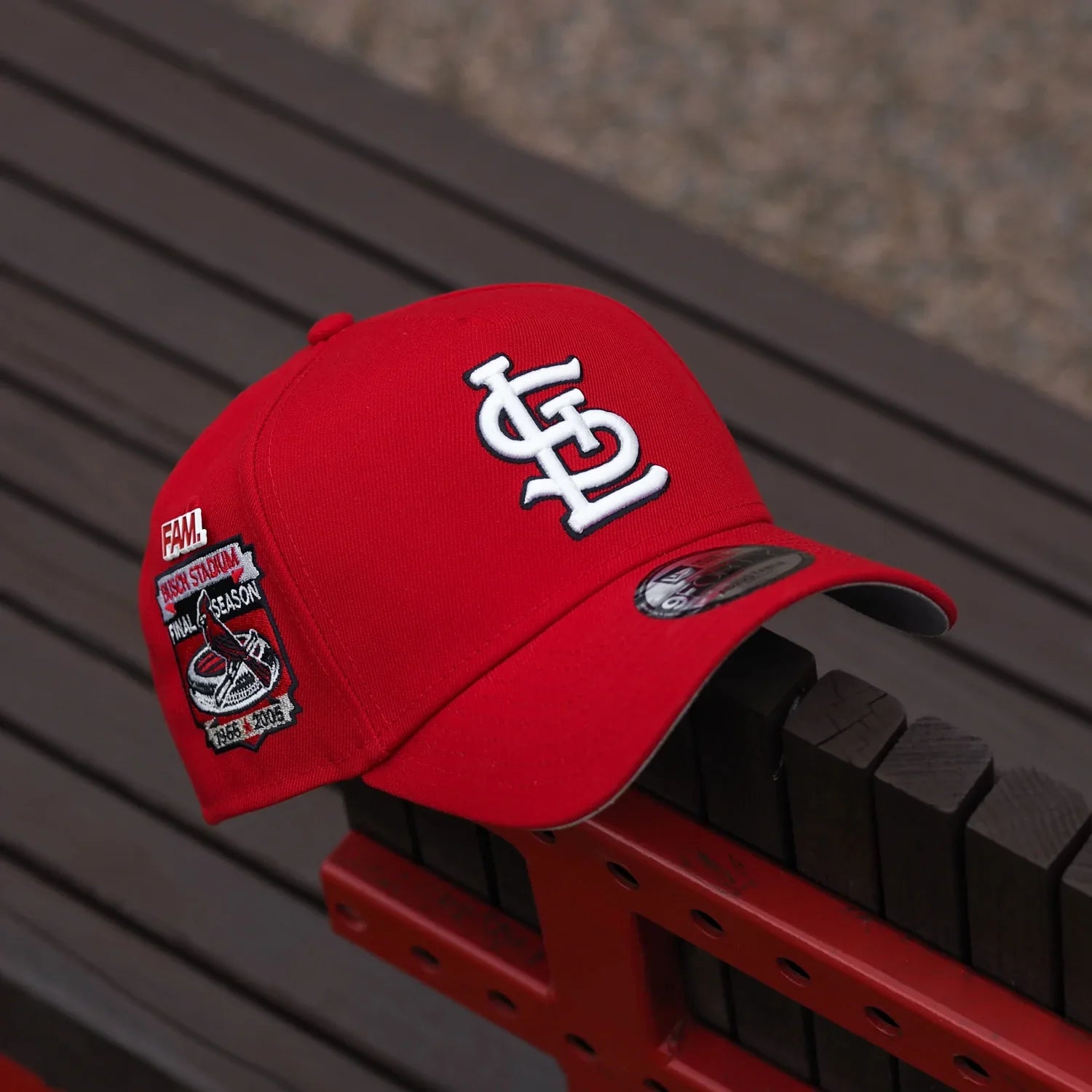 Red baseball cap with a logo on a red and black striped background
