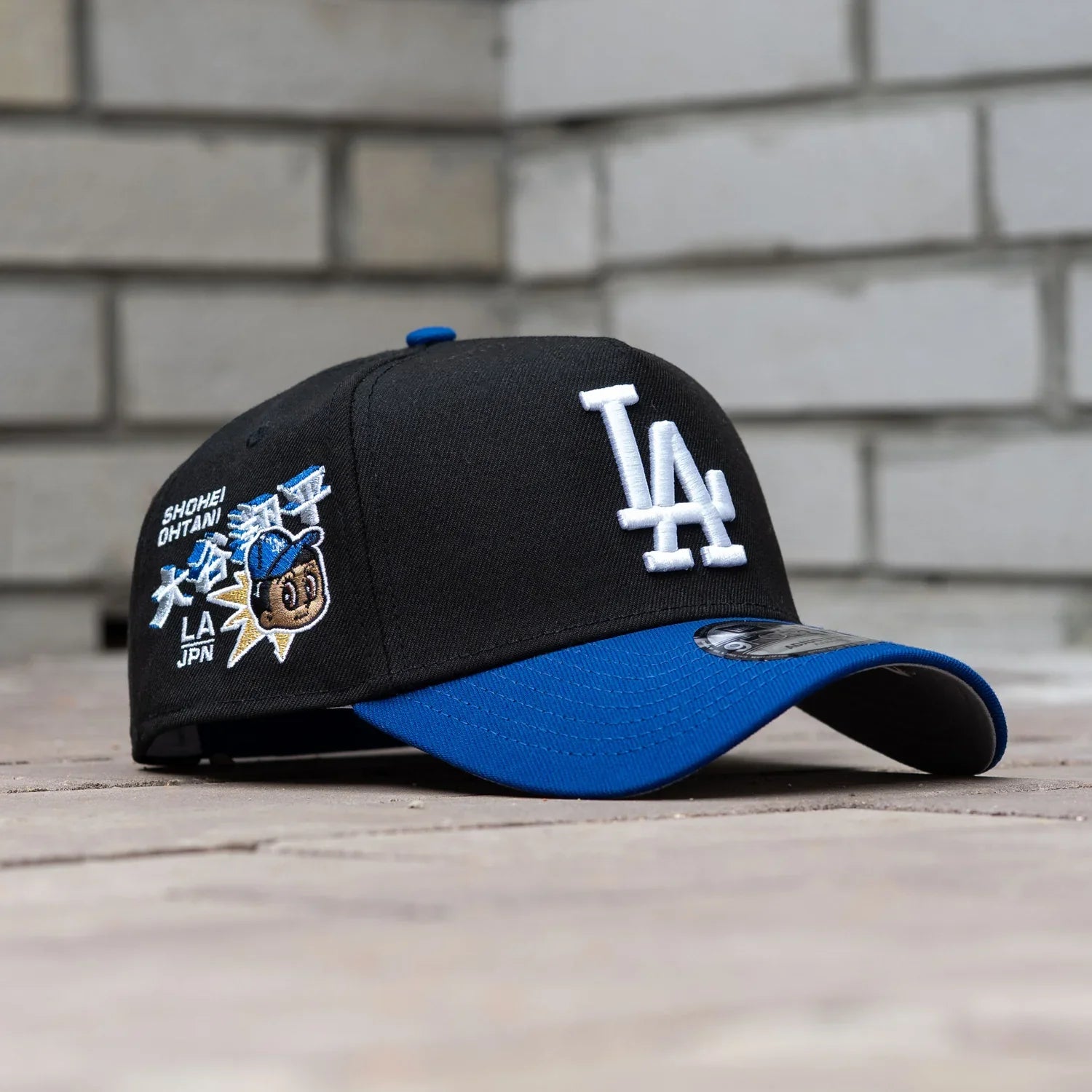 Black and blue baseball cap with LA logo on a wooden surface and brick wall background